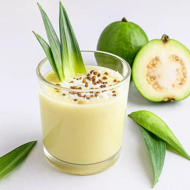 Glass of green smoothie/juice with guava and pineapple on a white background
